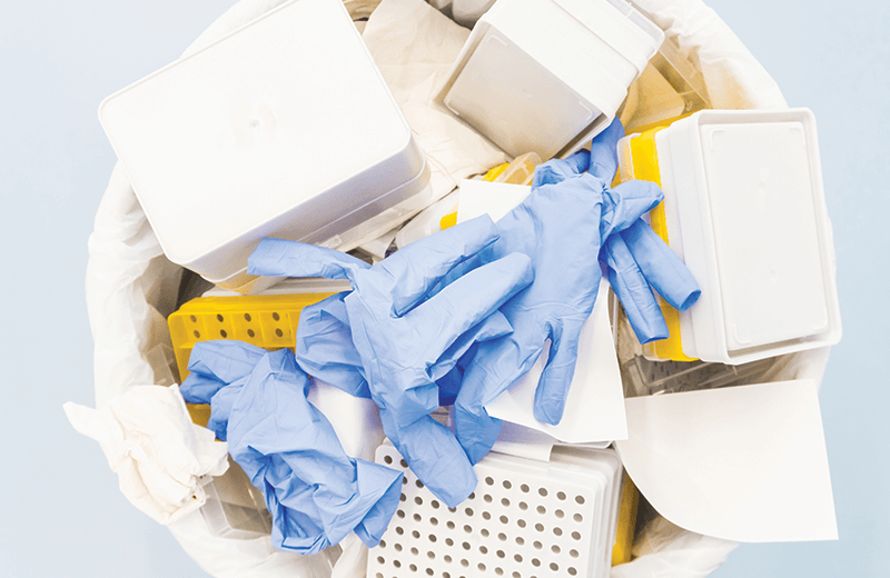 Latex gloves and plastic containers in a garbage can